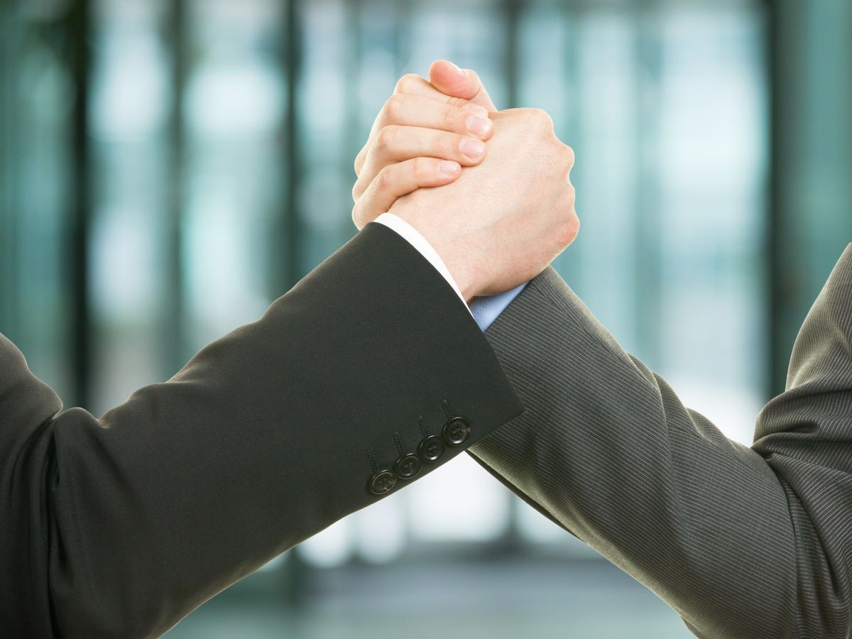 Two businessman shaking hands after the successful salary negotiation thanks to the career coach